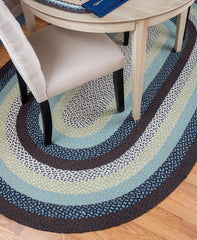 Braided rug under table in shades of blue, grey, white and soft green. 