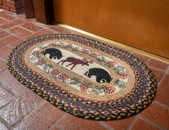 Braided rug with bear and moose silhouettes and pinecone border design
