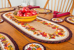 Braided table runner with Fall leaves themed design. Burgundy and black border with natural tan jute center.