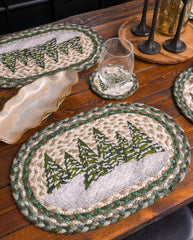Braided oval placemats and coasters with a green pine tree pattern on a rustic wooden dining table. For winter table scape. 