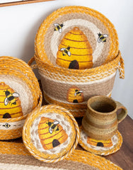 Braided jute basket with bee and beehive design in yellow, tan and white for summer feel. 