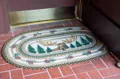 Braided jute rug with moose, tree and pinecone design as welcome mat